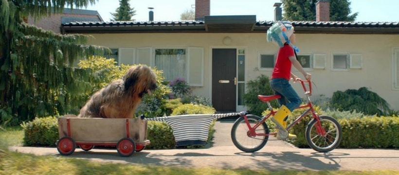 PB Extrait d'une publicité Petit Bateau, dans laquelle un petit garçon tire son chien depuis son vélo à l'aide de sa marinière