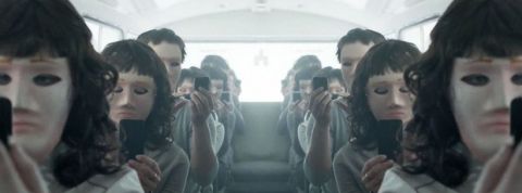 gens assis dans un bus aveec leur smartphone et des masques