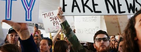 homme tenant une pancarte fake news dans une manifestation