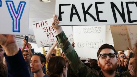 homme tenant une pancarte fake news dans une manifestation
