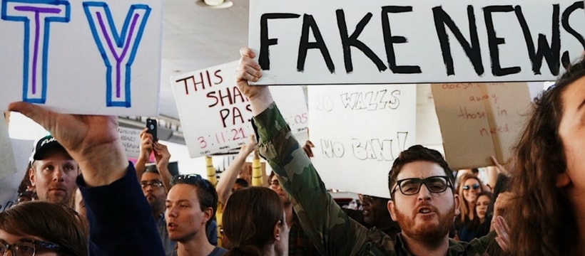 homme tenant une pancarte fake news dans une manifestation