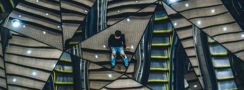 miroir un homme assis sur des escaliers, se reflétant dans plusieurs miroirs