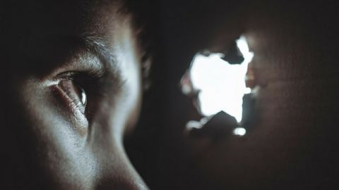 Un oeil d'enfant qui regarde dans le trou d'un mur