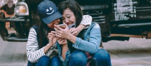 deux amies rient ensemble devant leur smartphone