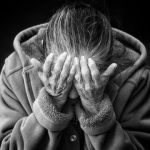 une femme se tient la tete entre ses mains