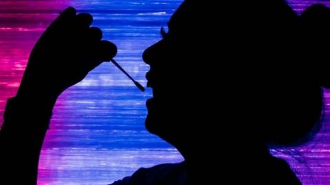 une femme en train de prélever son ADN avec un coton tige