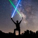 Un homme en train de brandir des lasers sur un ciel étoilé