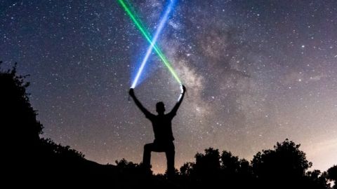 Un homme en train de brandir des lasers sur un ciel étoilé