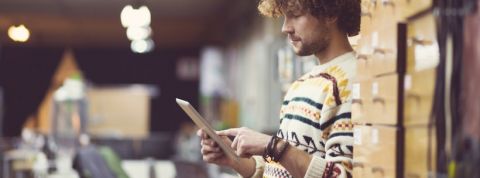 Amazon Un homme au milieu de cartons en train d'utiliser une tablette