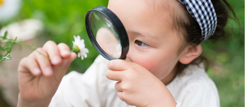 beauty petite fille qui regarde une marguerite avec une loupe