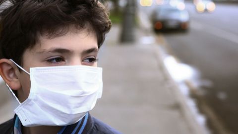 enfant avec un masque respiratoire dans la rue