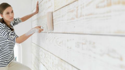 une femme qui peint une maison