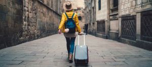 une femme de dos qui part en vacances avec sa valise