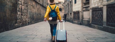 une femme de dos qui part en vacances avec sa valise