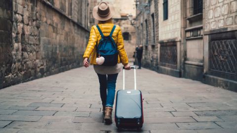 une femme de dos qui part en vacances avec sa valise