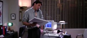 Chandler Bing au téléphone, dans son bureau, dans la série Friends