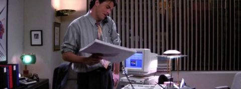 Chandler Bing au téléphone, dans son bureau, dans la série Friends