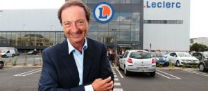 Michel Edouard Leclerc posant devant un magasin Leclerc, avec le sourire