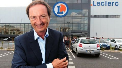 Michel Edouard Leclerc posant devant un magasin Leclerc, avec le sourire
