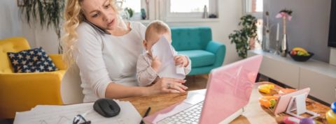 workingmum Une jeune mère en train de travailler avec son enfant dans les bras