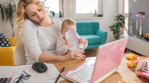 Une jeune mère en train de travailler avec son enfant dans les bras