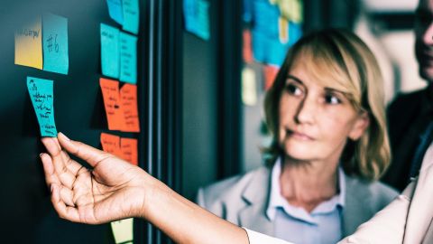 salariés devant un tableau de post-it travaillant en méthode agile