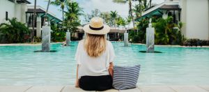 Une femme blonde assise de dos au bord d'une piscine
