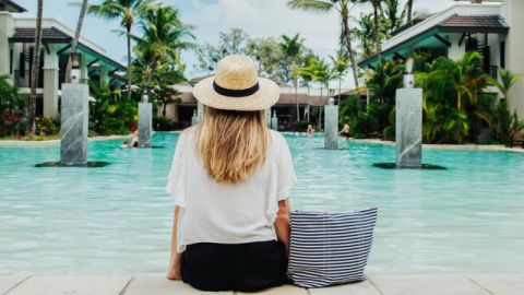 Une femme blonde assise de dos au bord d'une piscine