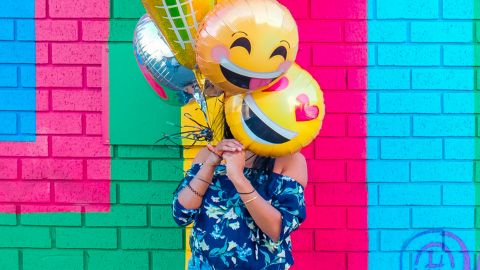 Une femme avec des ballons en forme d'emoji