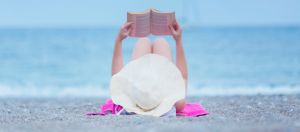 Une femme allongée sur la plage en train de lire un livre