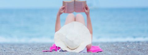 Quels livres lire cet été ? Une femme allongée sur la plage en train de lire un livre