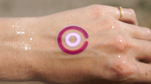 Une main avec un tatouage violet dessus.