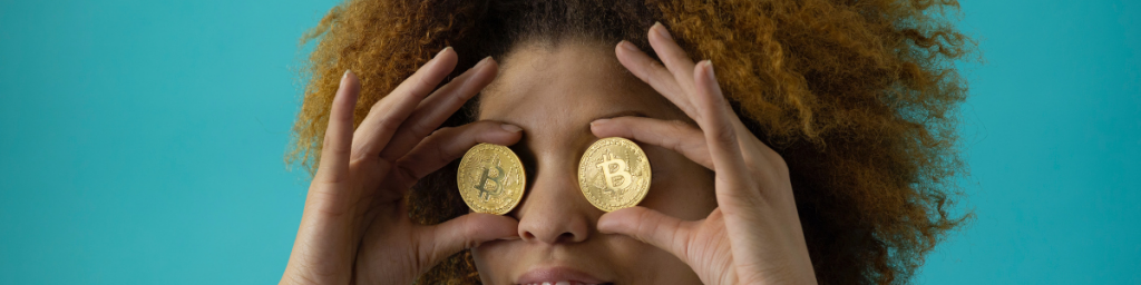 Une femme tient deux bitcoins au niveaux de ses yeux