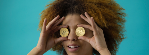 Les cryptomonnaies, une révolution Une femme tient deux bitcoins au niveaux de ses yeux