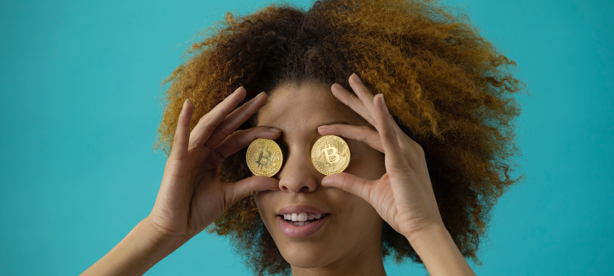 Les cryptomonnaies, une révolution Une femme tient deux bitcoins au niveaux de ses yeux