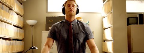 Un homme médite avec un casque sur les oreilles dans une maison