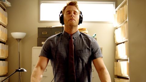 Un homme médite avec un casque sur les oreilles dans une maison