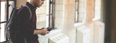 Comment bien utiliser la technologie à la fac Une jeune homme consulte son smartphone à la pause entre deux cours