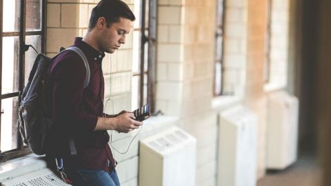 Une jeune homme consulte son smartphone à la pause entre deux cours