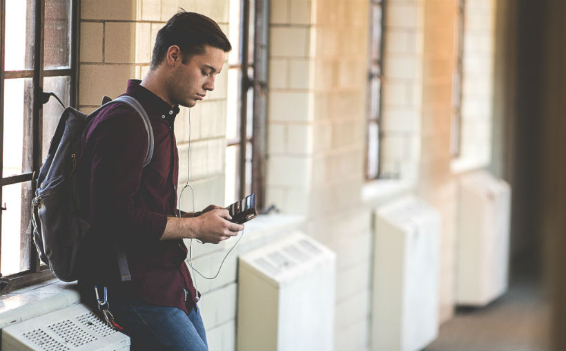 Comment bien utiliser la technologie à la fac Une jeune homme consulte son smartphone à la pause entre deux cours