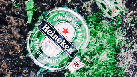 Bouteille de bière Heineken verte brisée sur la plage