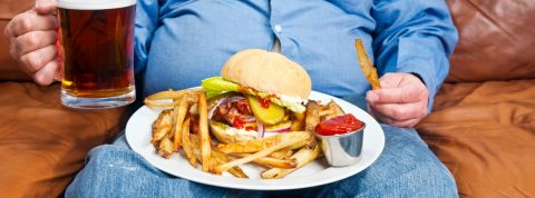 La malbouffe continue de progresser en Europe Un homme dans son canapé avec une bière et un burger