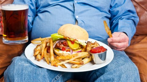 Un homme dans son canapé avec une bière et un burger