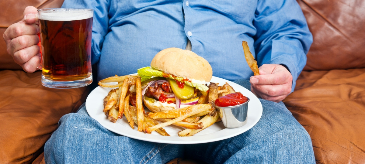 La malbouffe continue de progresser en Europe Un homme dans son canapé avec une bière et un burger