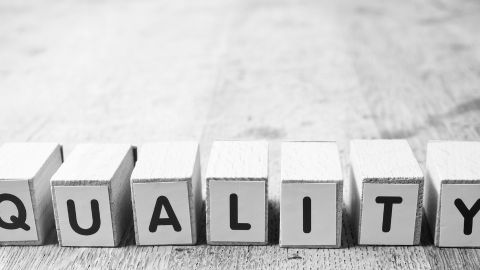 Le mot qualité présenté en petits cubes noir et blanc