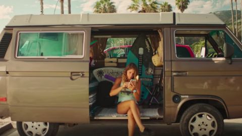 Une femme regarde son téléphone dans son van