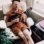 Un homme en train de se prélasser dans un fauteuil avec une guitare