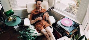 Un homme en train de se prélasser dans un fauteuil avec une guitare