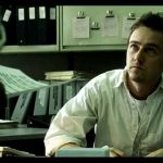 un homme assis sur son bureau regarde son patron