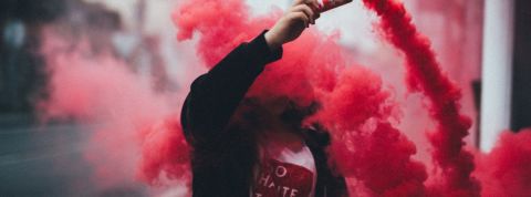 Comment les start-up crée une économie parallèle illégale Un homme dans un sweat noir en train de propager un fumigène rouge